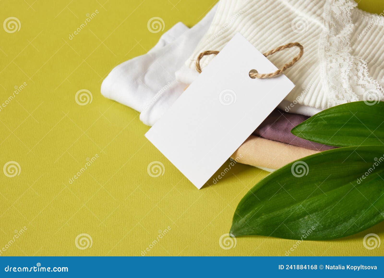 folded lingerie and white blank tag for marking or inscription on green background, eco lingerie concept