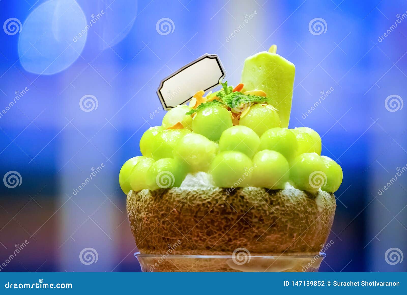 green melon ball  are arranged on the top of bingsu (korean ice-cream style) and decorated with green tea ice-cream and mint