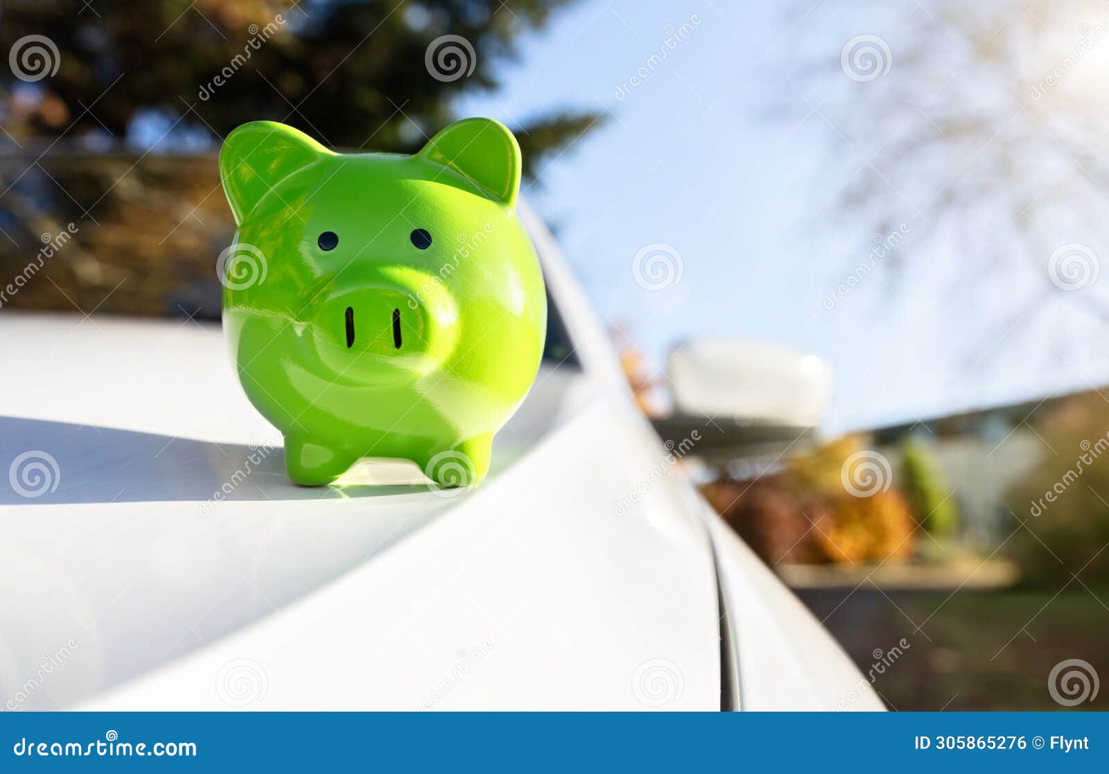 green piggy bank money box on top of car hood, new vehicle purchase, insurance or driving and motoring cost