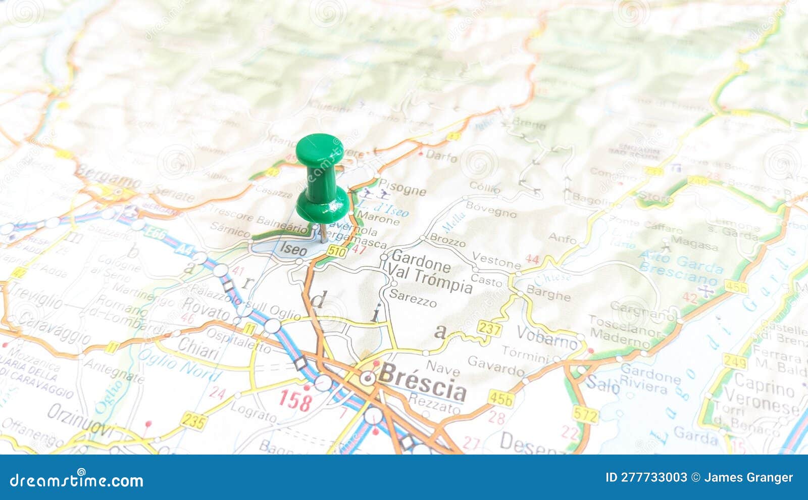 a green pin stuck in lake iseo on a map of italy