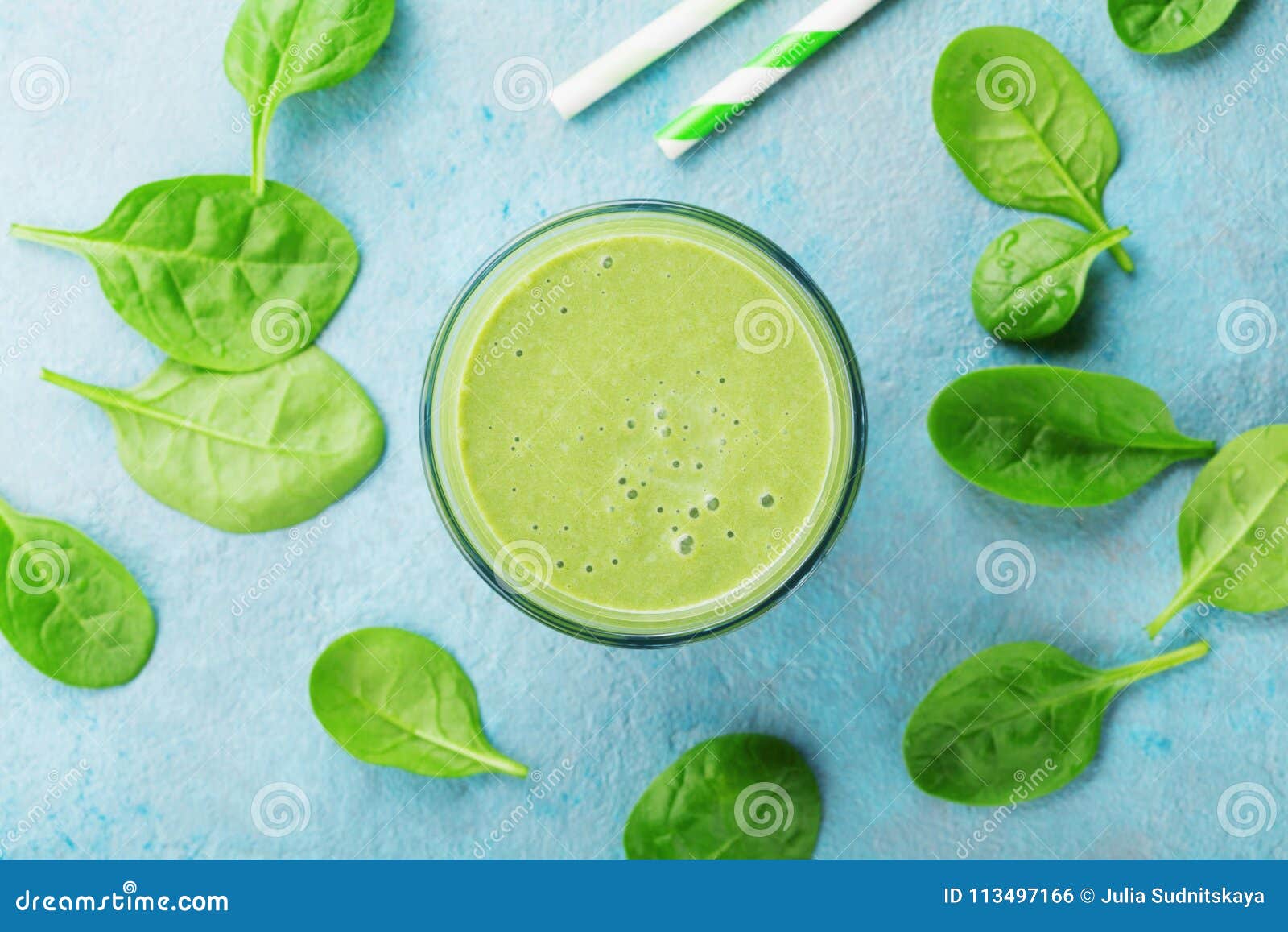 green spinach smoothie on blue table top view. detox and diet food for breakfast.