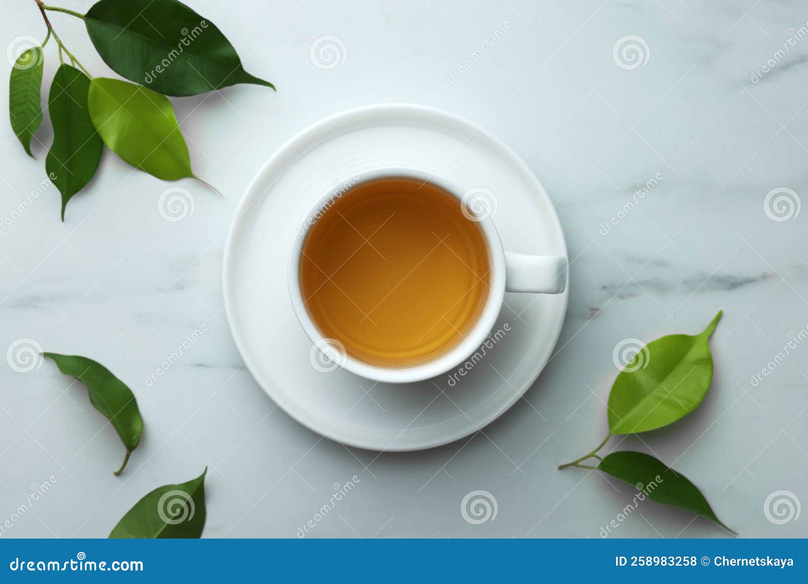 Green Tea in Cup with Saucer and Leaves on White Marble Table, Flat Lay