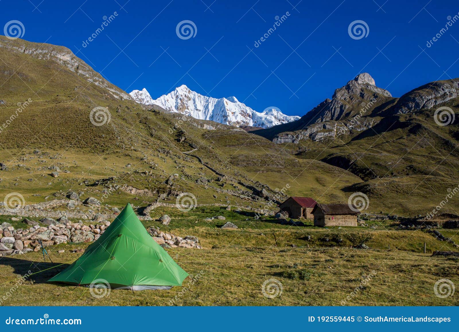 green tent in an empty camping at the bottom of beautiful snow mountain