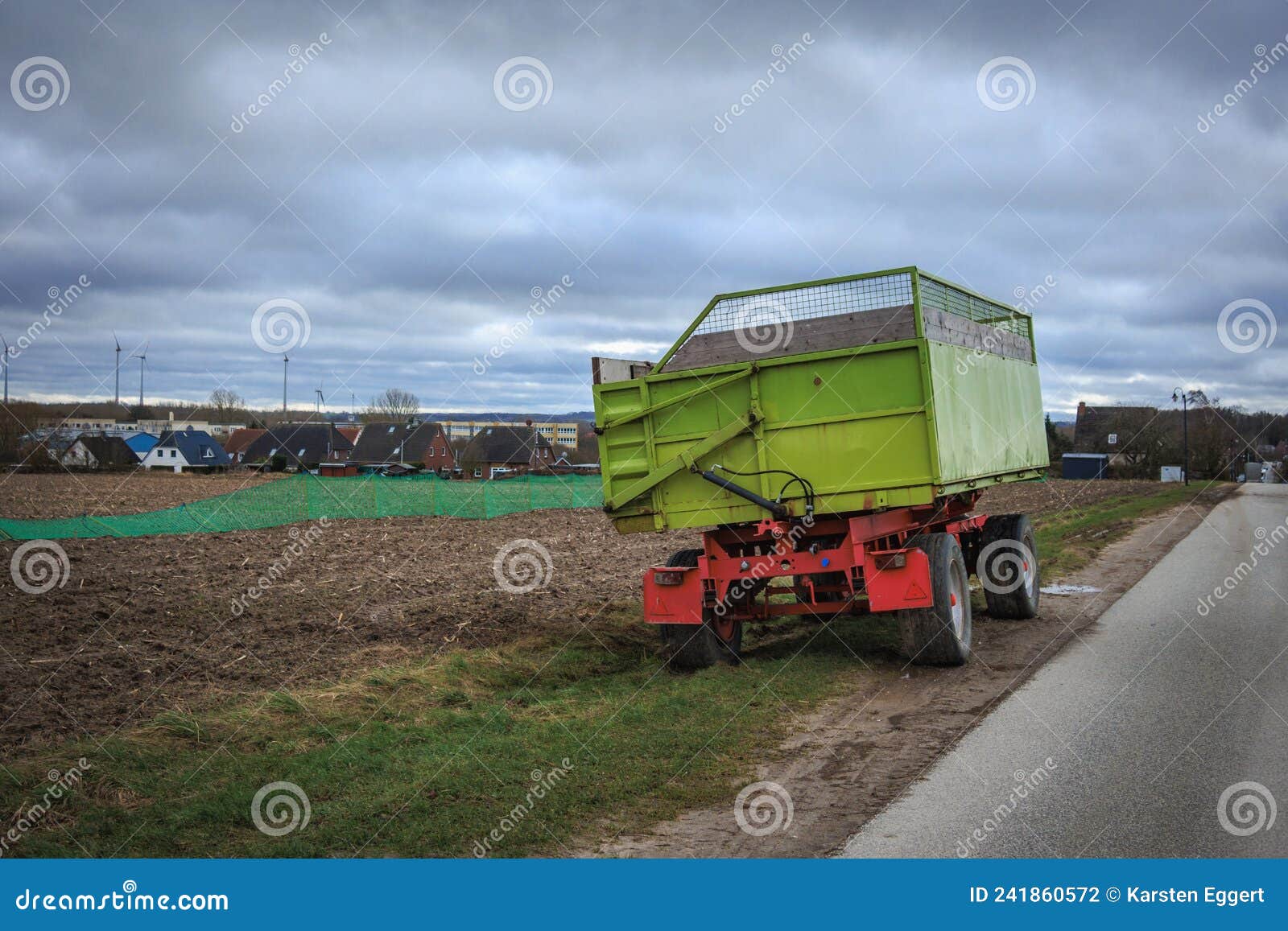 Green Tractor Trailer Stands on the Roadside Next To a Field Stock