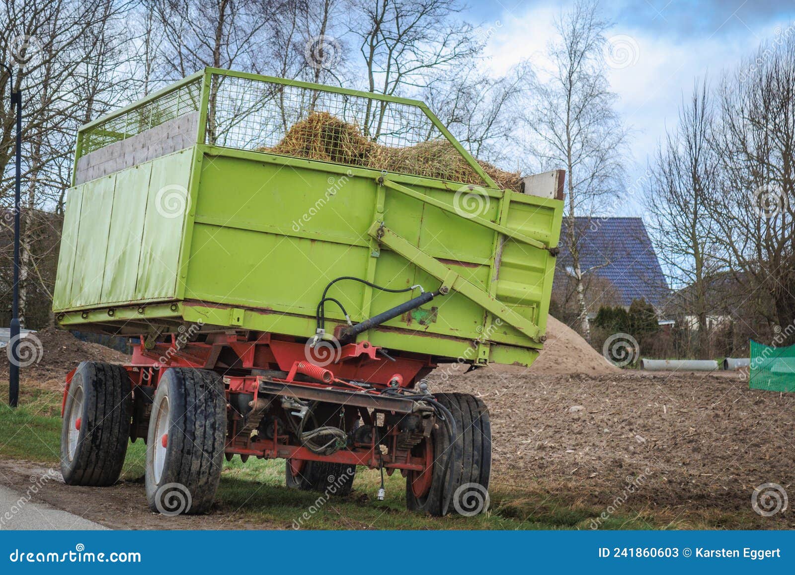 Green Tractor Trailer Stands on the Roadside Next To a Field Stock