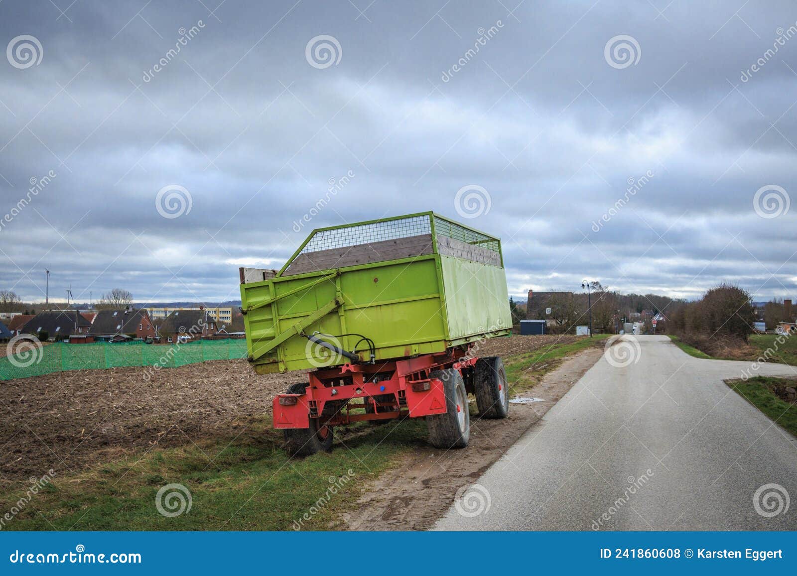 Green Tractor Trailer Stands on the Roadside Next To a Field Stock