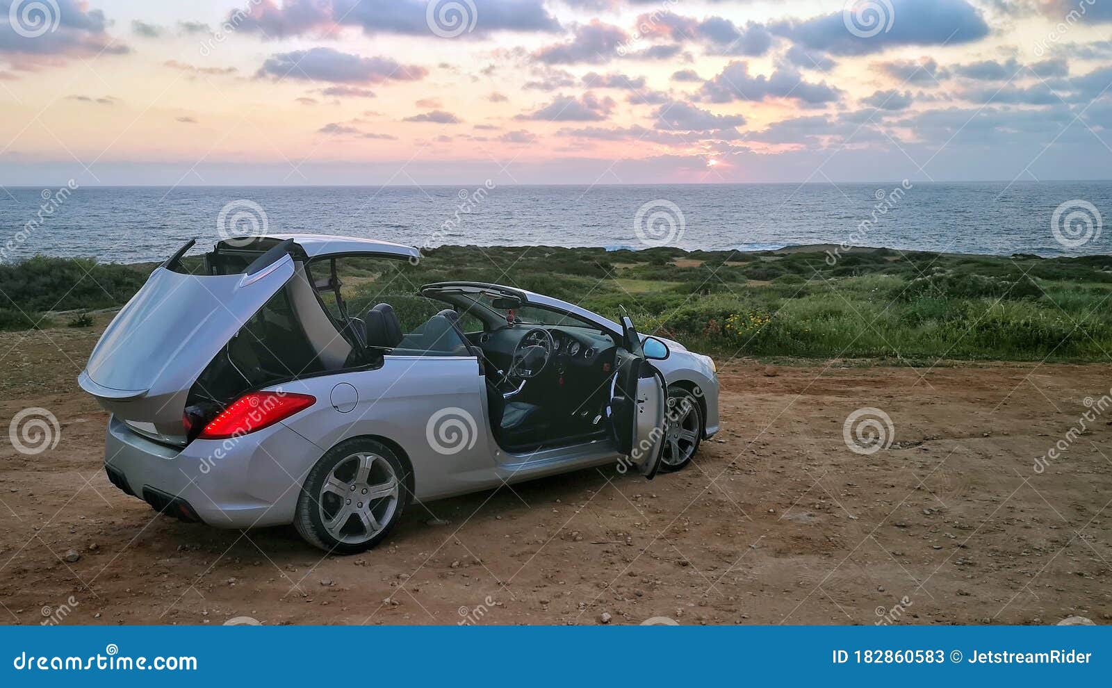 Grey Convertible Car With With Roof Mechanism In Operation Against The