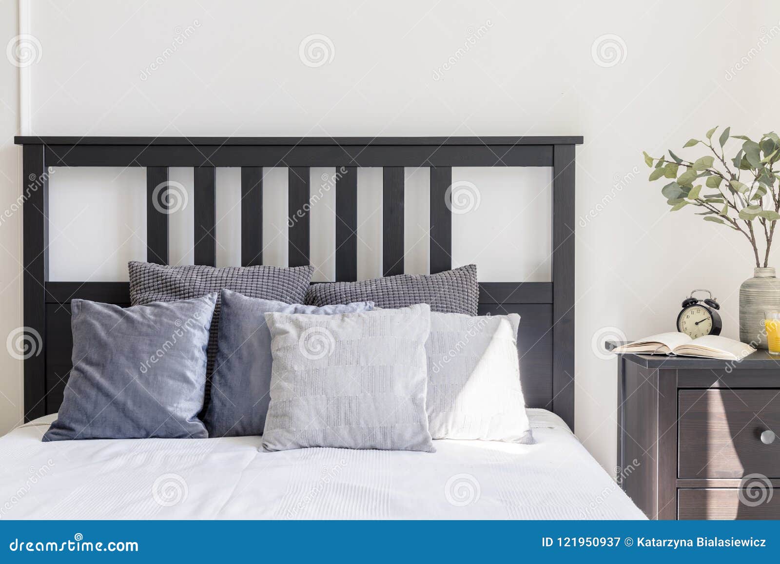 Grey and White Pillows on Bed with Black Headboard in Simple Bed Stock