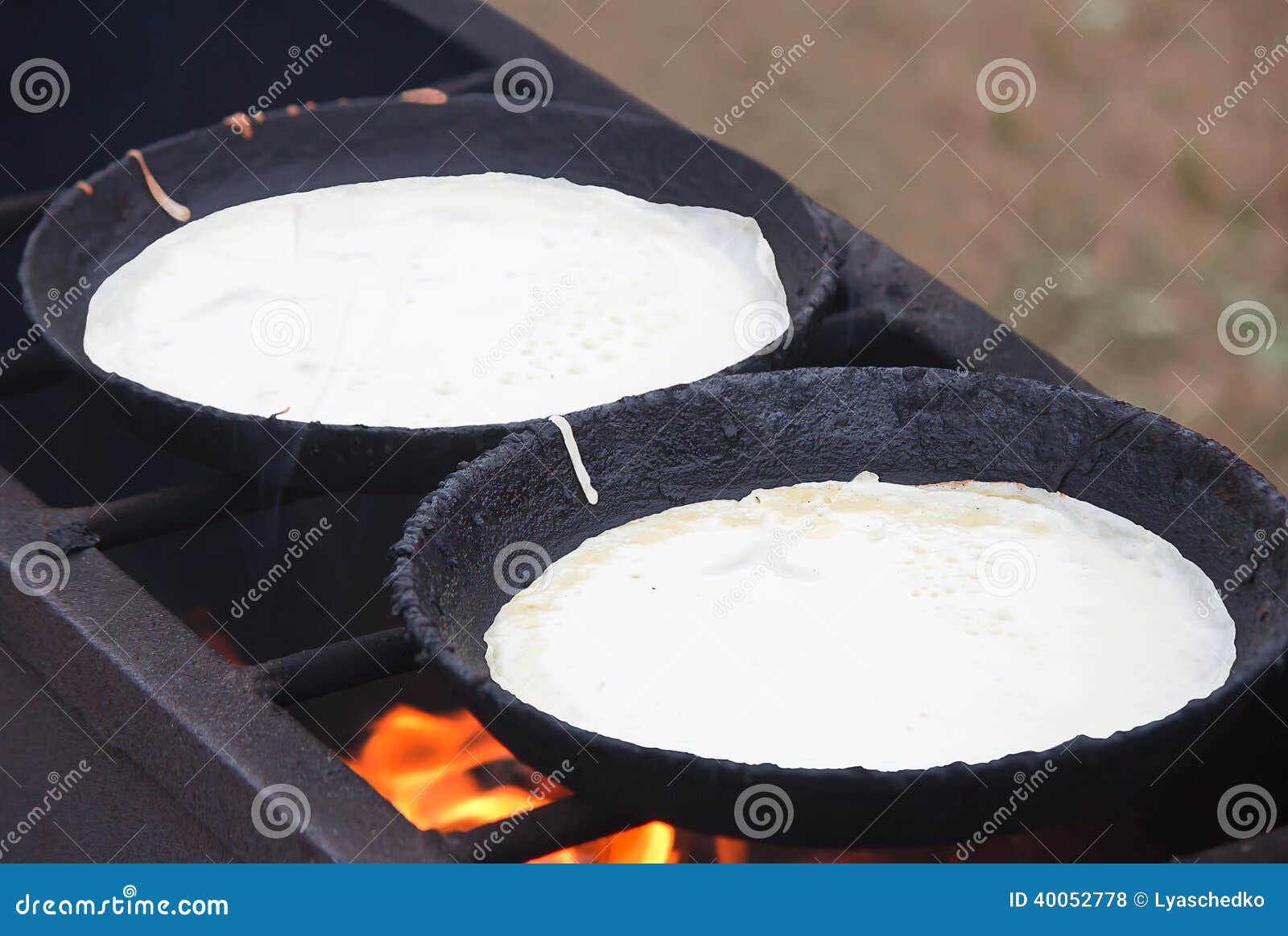 The Grill and Two Frying Pans, on Them are Fried Pancakes. Stock Photo