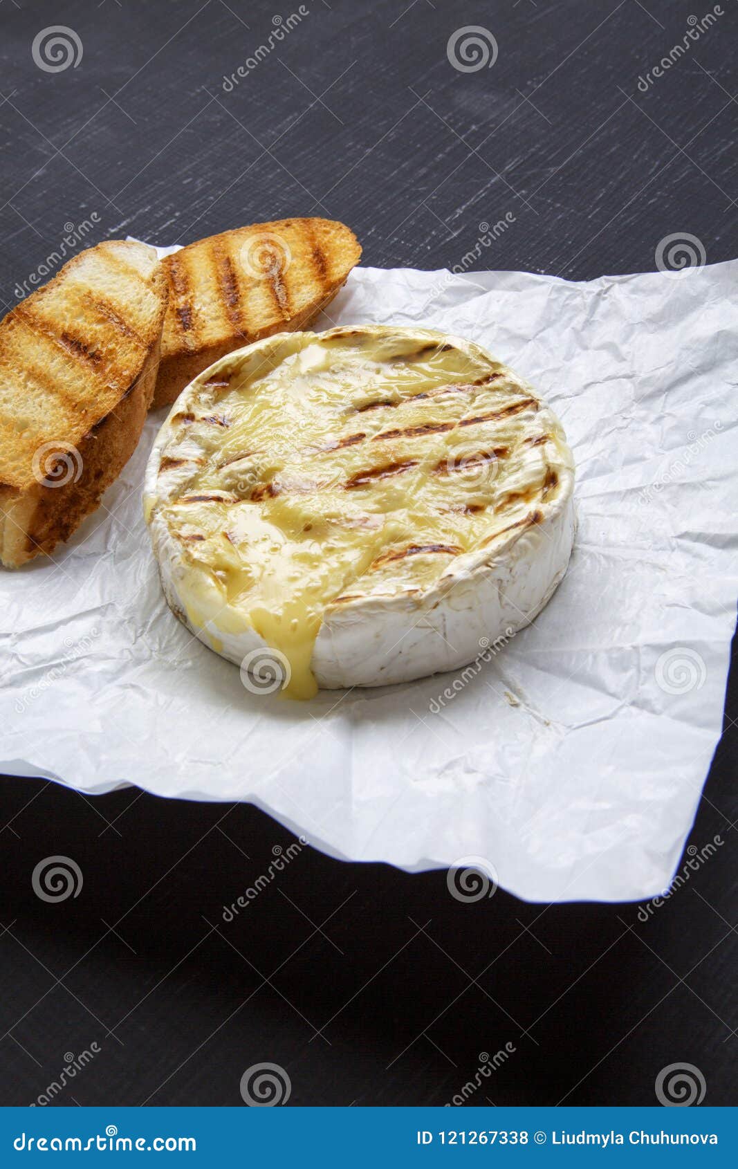 Grilled Camembert Cheese on a Black Background, Side View. Stock Photo