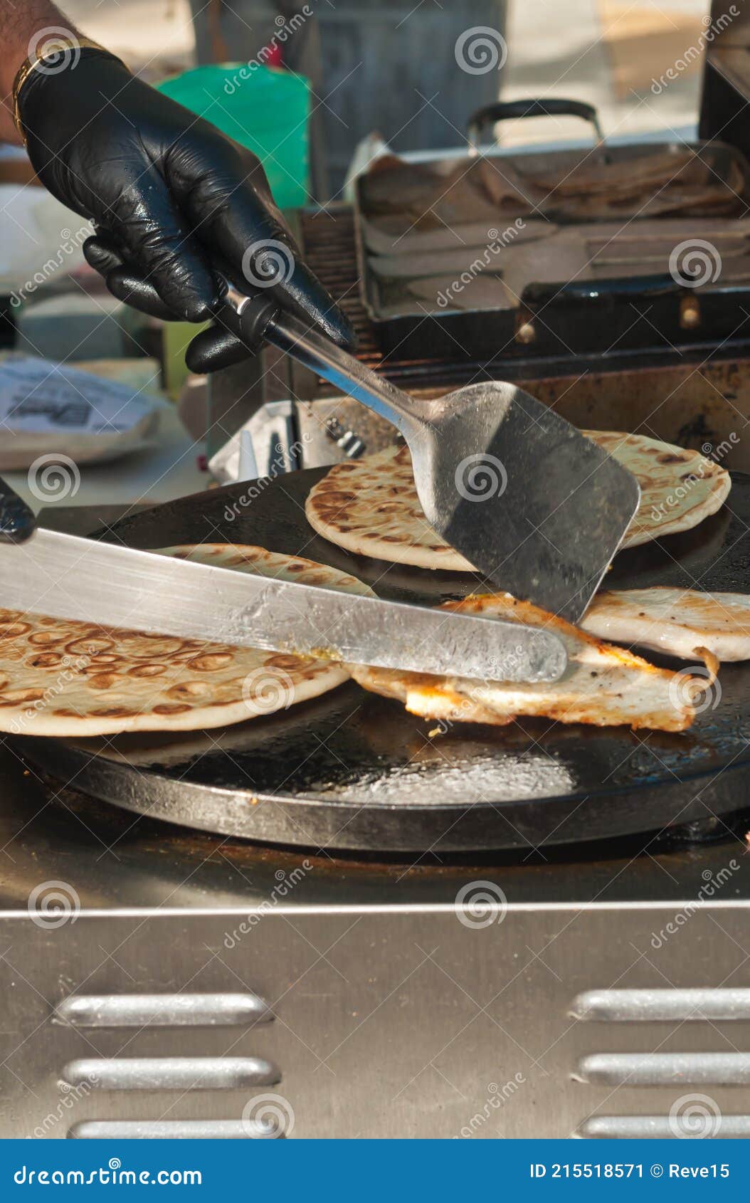 grilled chicken  and flat bread in a flat grill, being moved by a vender with knife and spatula