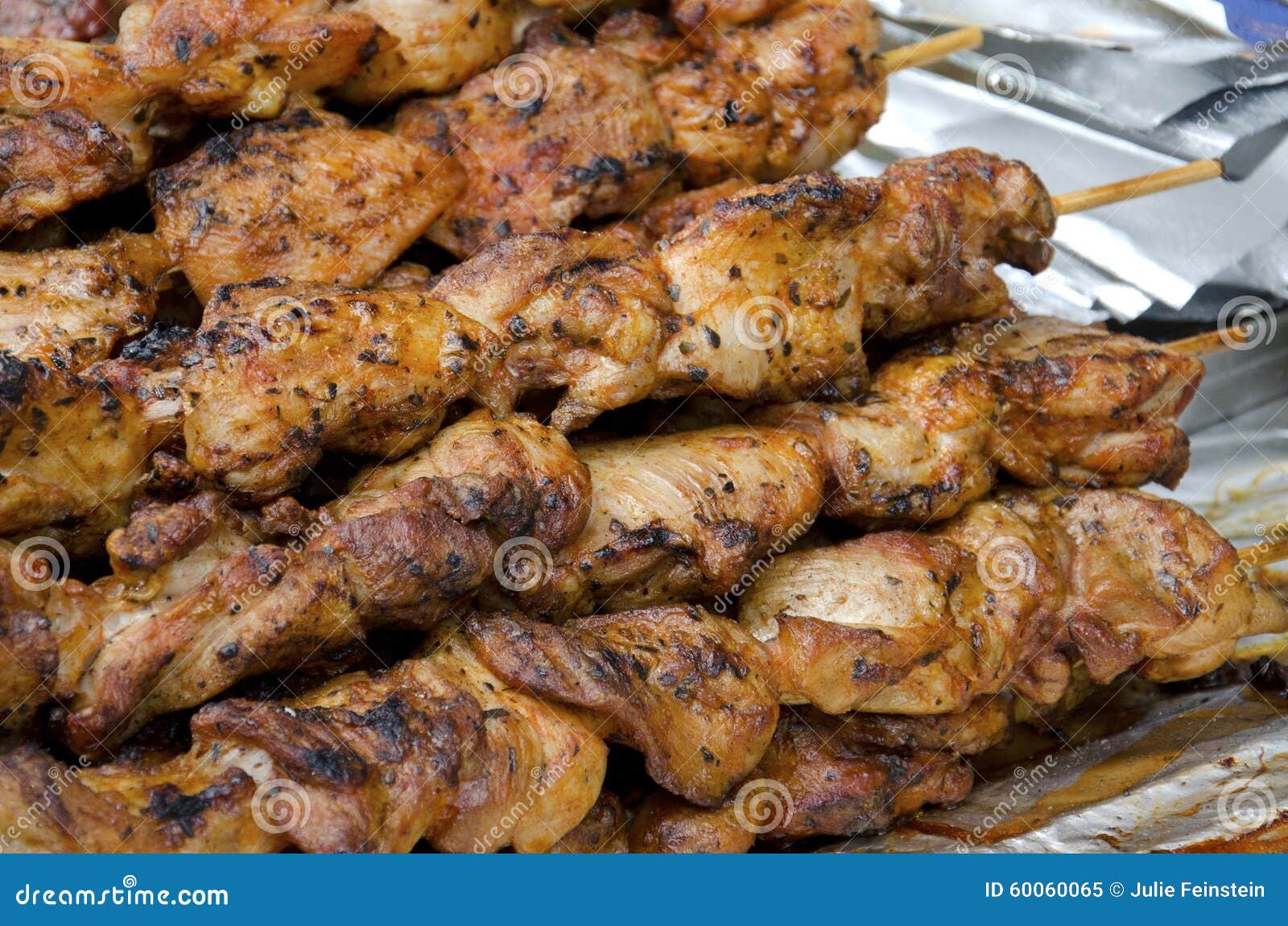 A pile of seasoned spicy grilled chicken on skewers.
