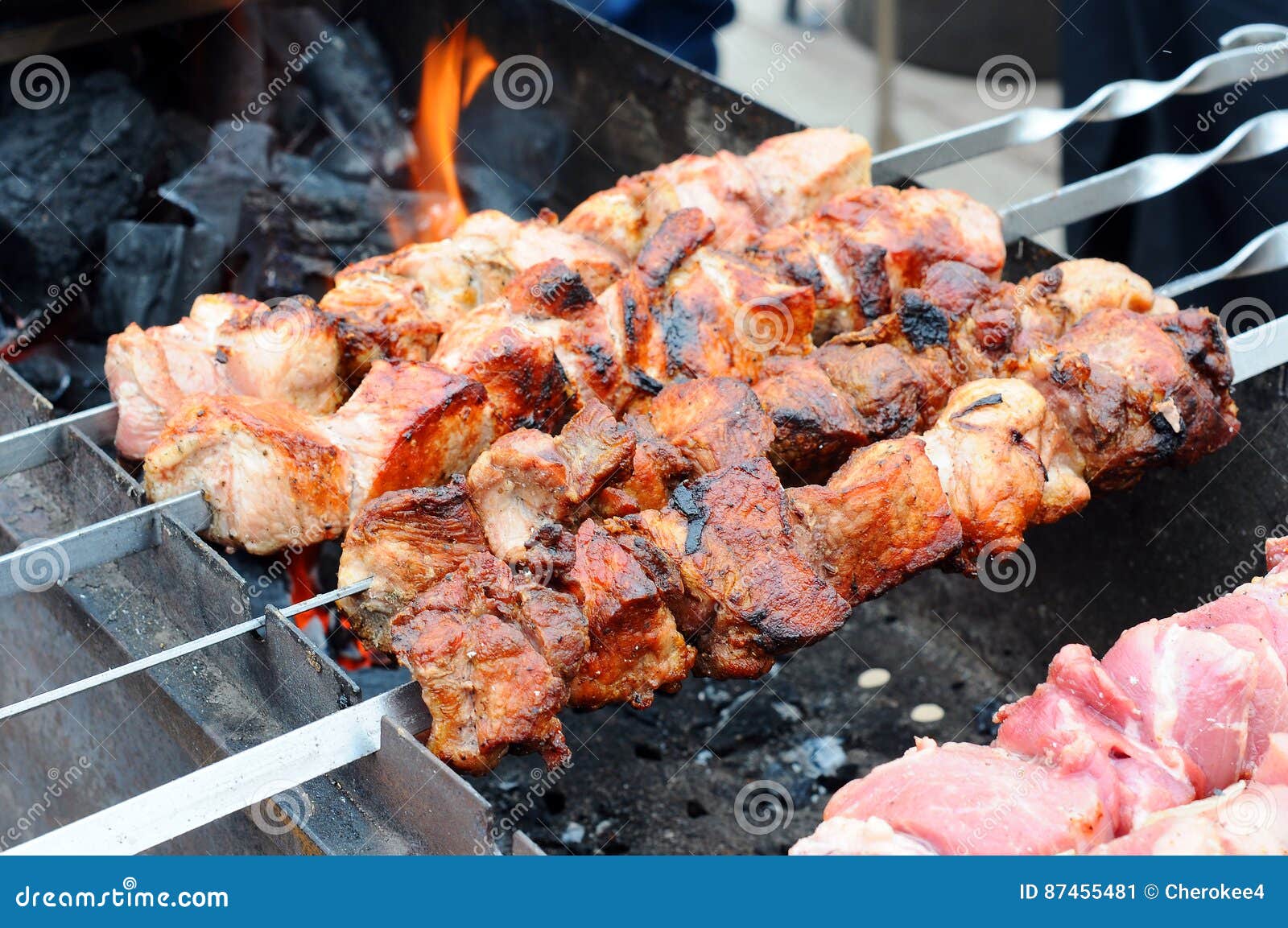 Grilling marinated shashlik on a grill. Shashlik is a form of Shish kebab  popular in Eastern, Central Europe and other places. Shashlyk (meaning  skewered meat) was originally made of lamb. Stock Photo