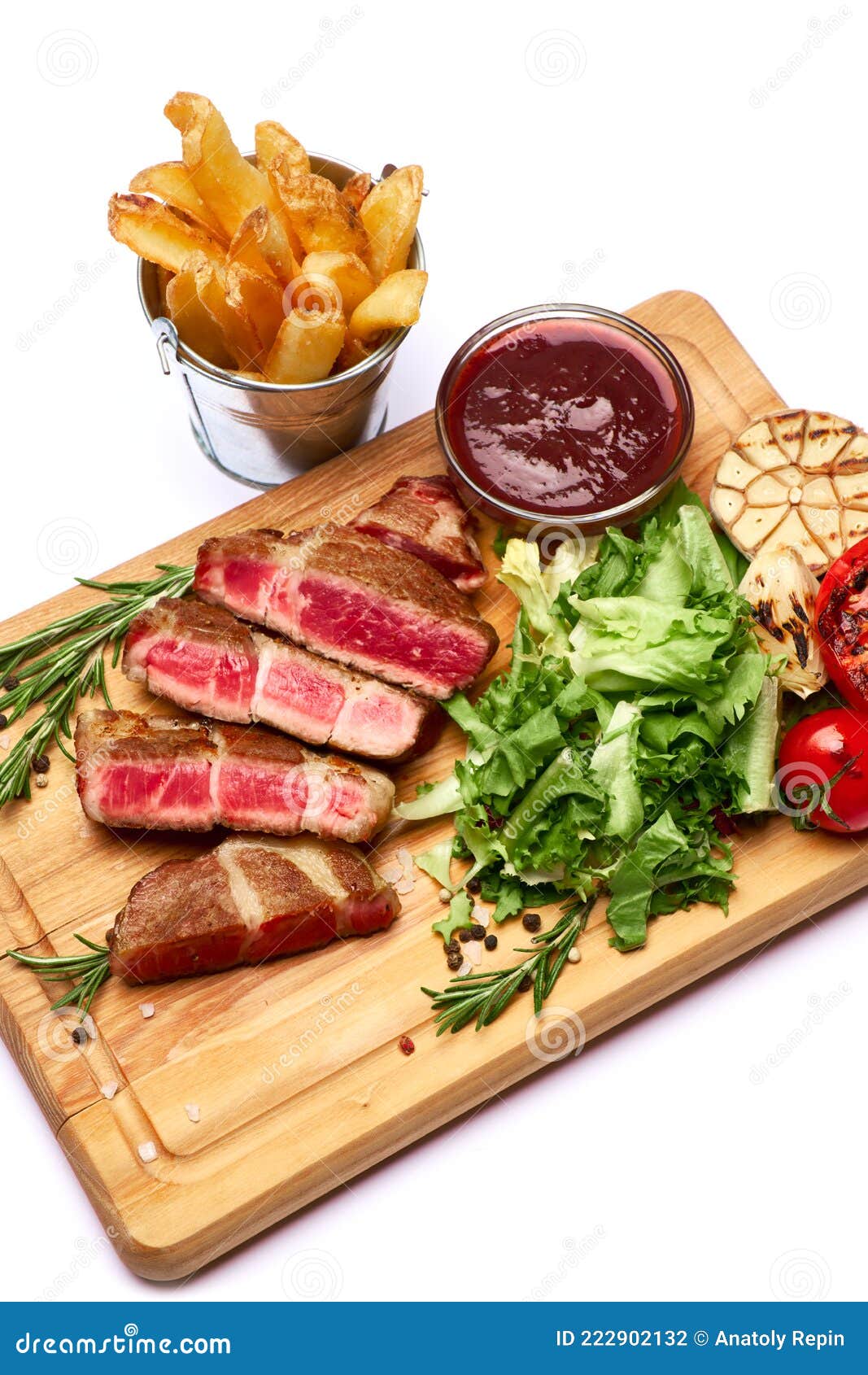 grilled sliced roated beef steaks, potato and sauce on wooden cutting board