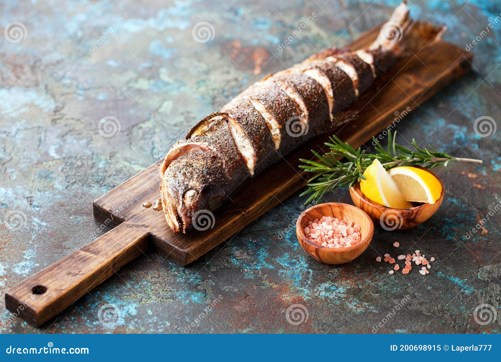 grilled whole humpback salmon fish with lemon on a wooden cutting board