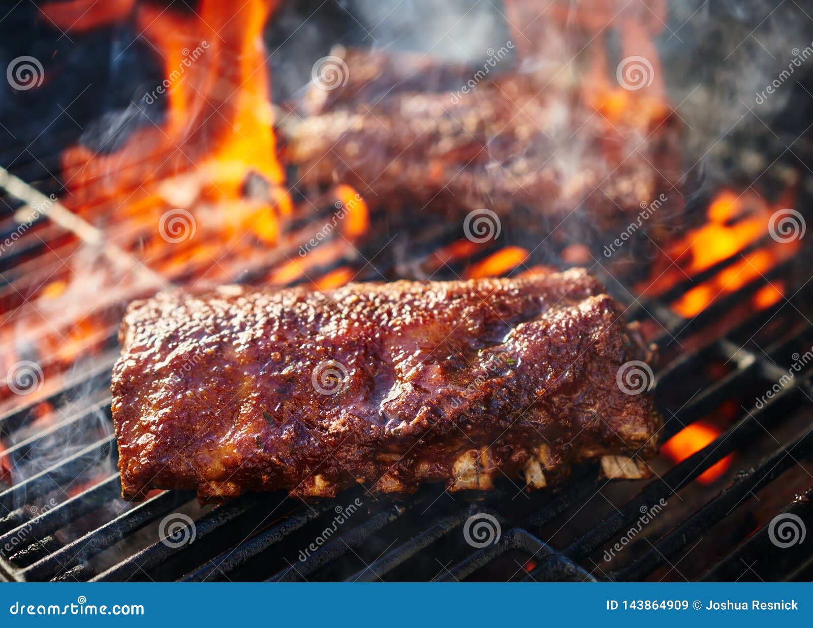 grilling barbecue ribs on flaming grill