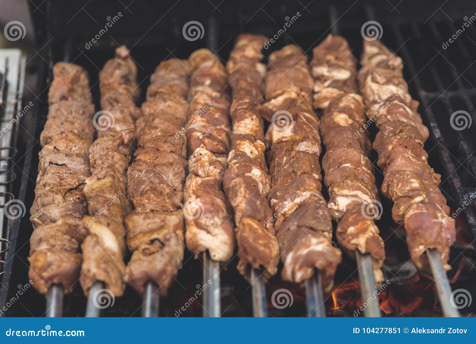 Grilling marinated shashlik preparing on a barbecue grill over charcoal.  Shashlik is a form of Shish kebab popular in Eastern Europe. Shashlyk (meaning  skewered meat) was originally made of lamb. Stock Photo