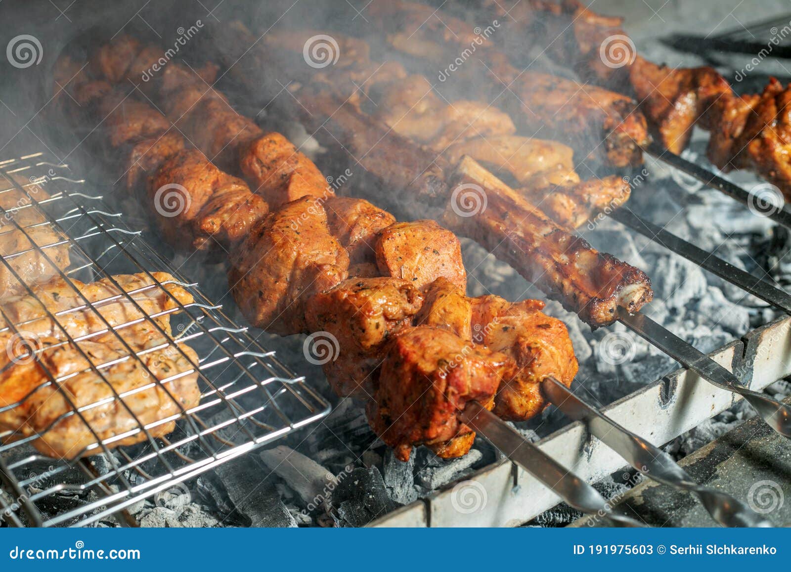 Grilling marinated shashlik preparing on a barbecue grill over charcoal.  Shashlik is a form of Shish kebab popular in Eastern Europe. Shashlyk (meaning  skewered meat) was originally made of lamb. Stock Photo