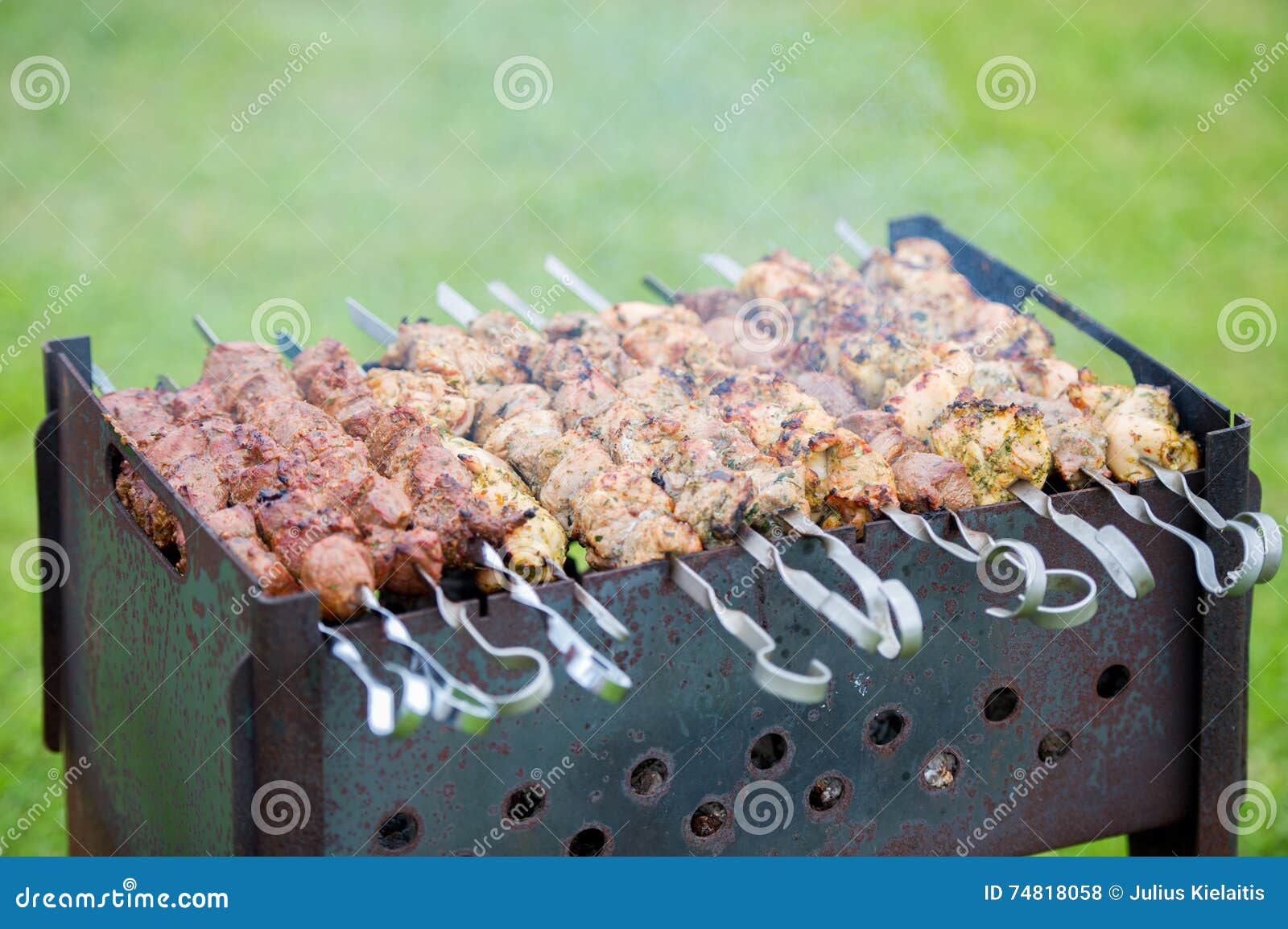 Grilling marinated shashlik preparing on a barbecue grill over charcoal.  Shashlik is a form of Shish kebab popular in Eastern Europe. Shashlyk (meaning  skewered meat) was originally made of lamb. Stock Photo