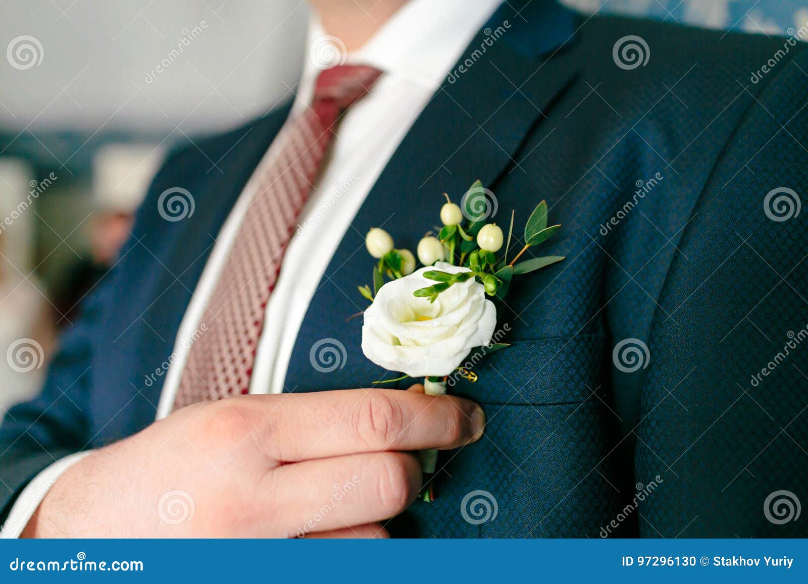 groom is pinning a boutonniere to a suit. wedding preparation