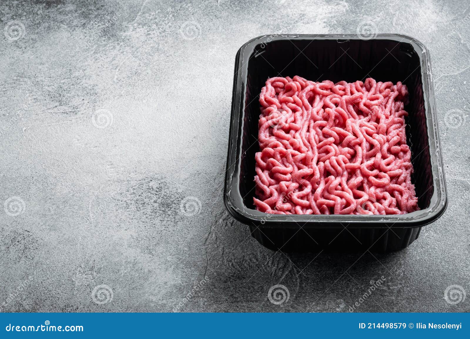 Ground Beef Meat in Plastic Tray, on Gray Stone Background, with Copy
