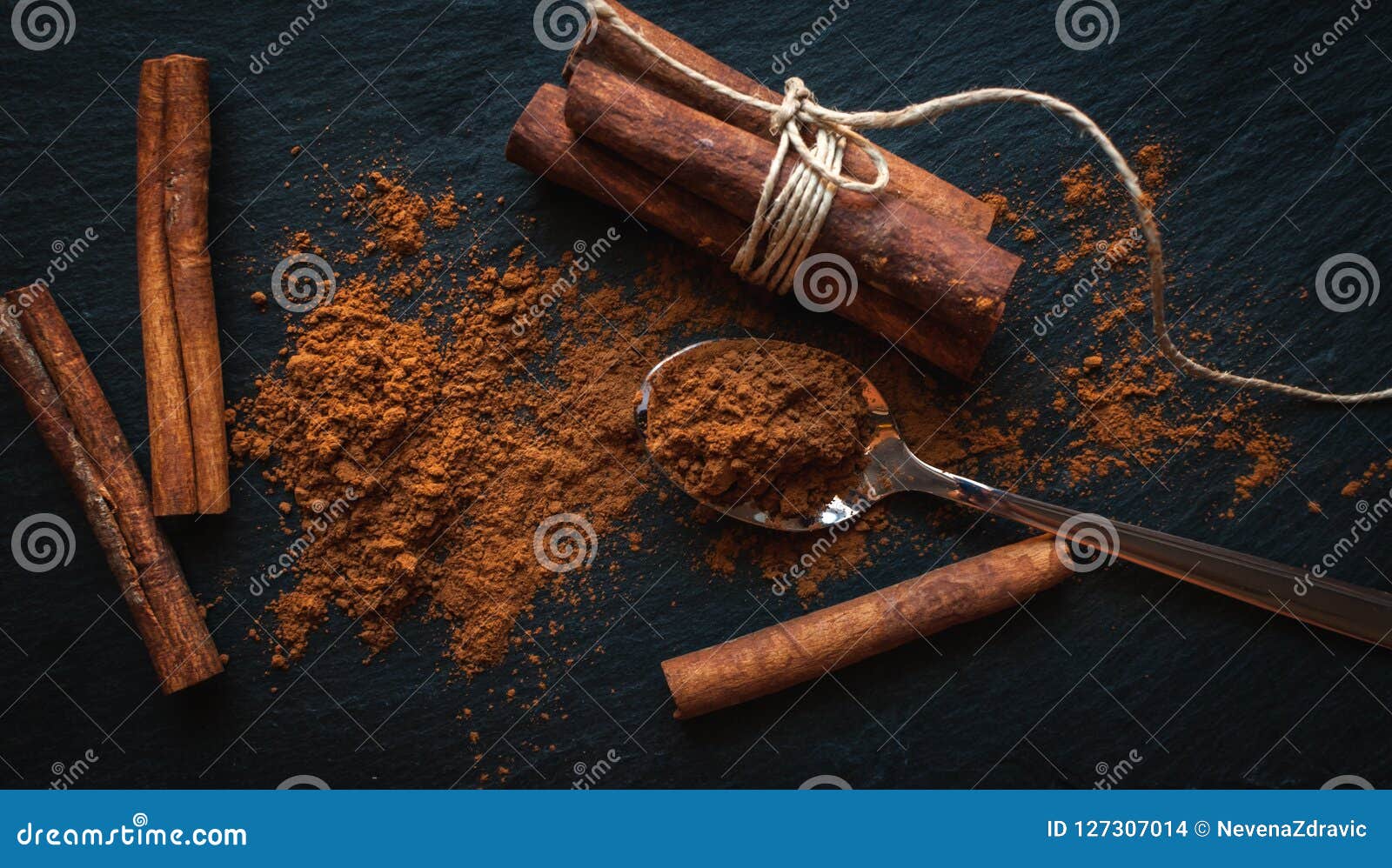 Ground Cinnamon in Teaspoon, and Cinnamon Sticks on Dark Background