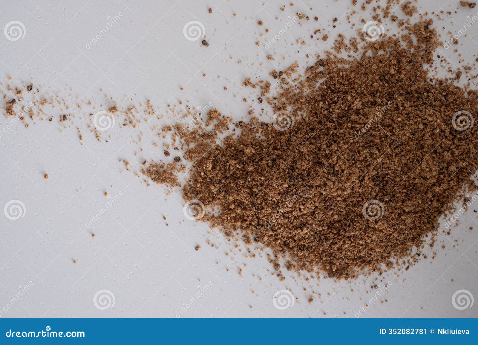ground clove powder is spread on a white background, showcasing its fine texture and rich brown color