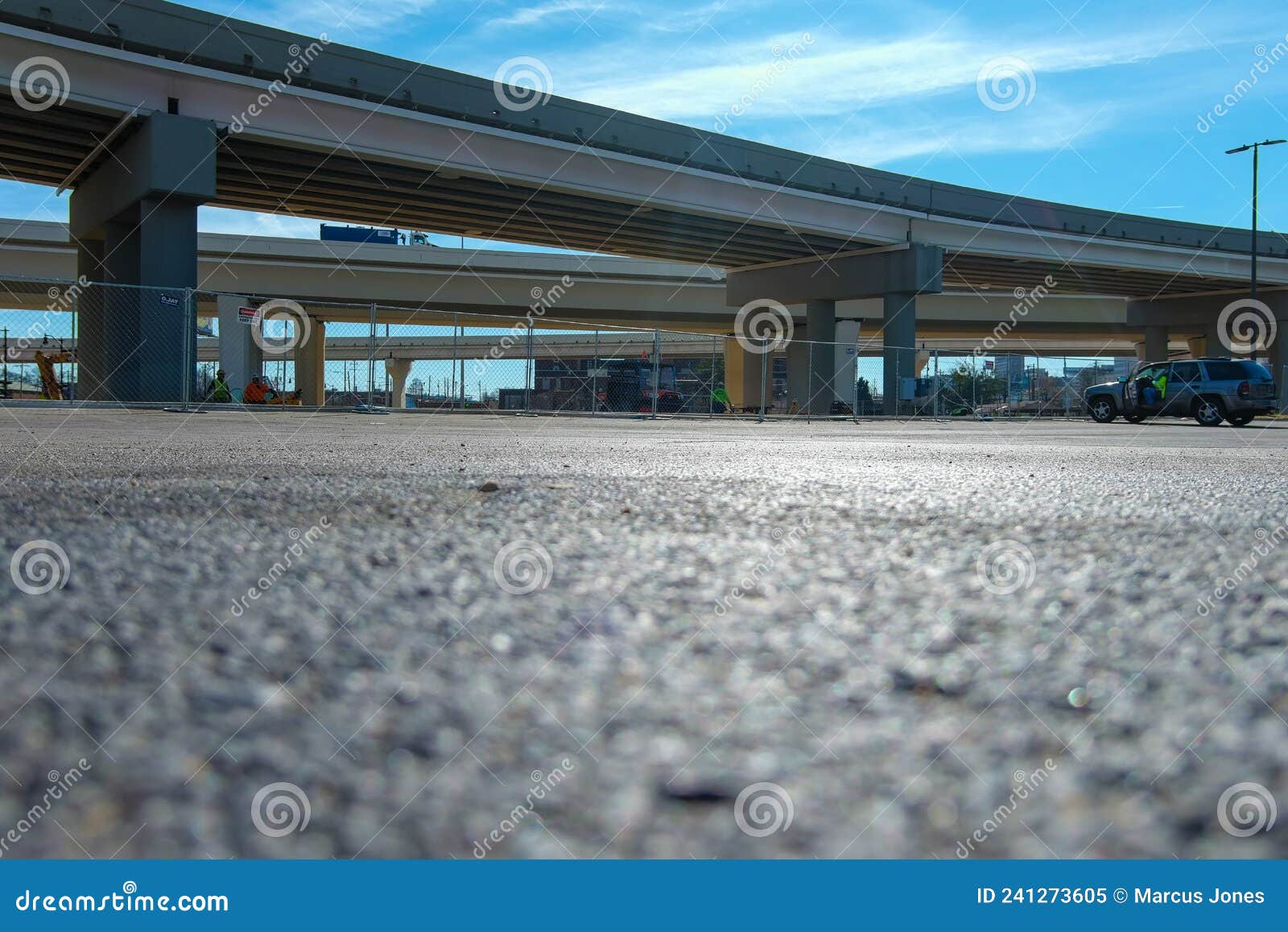 a ground level shot of a freeway over pass with a man in a yellow safety jacket sitting in an suv