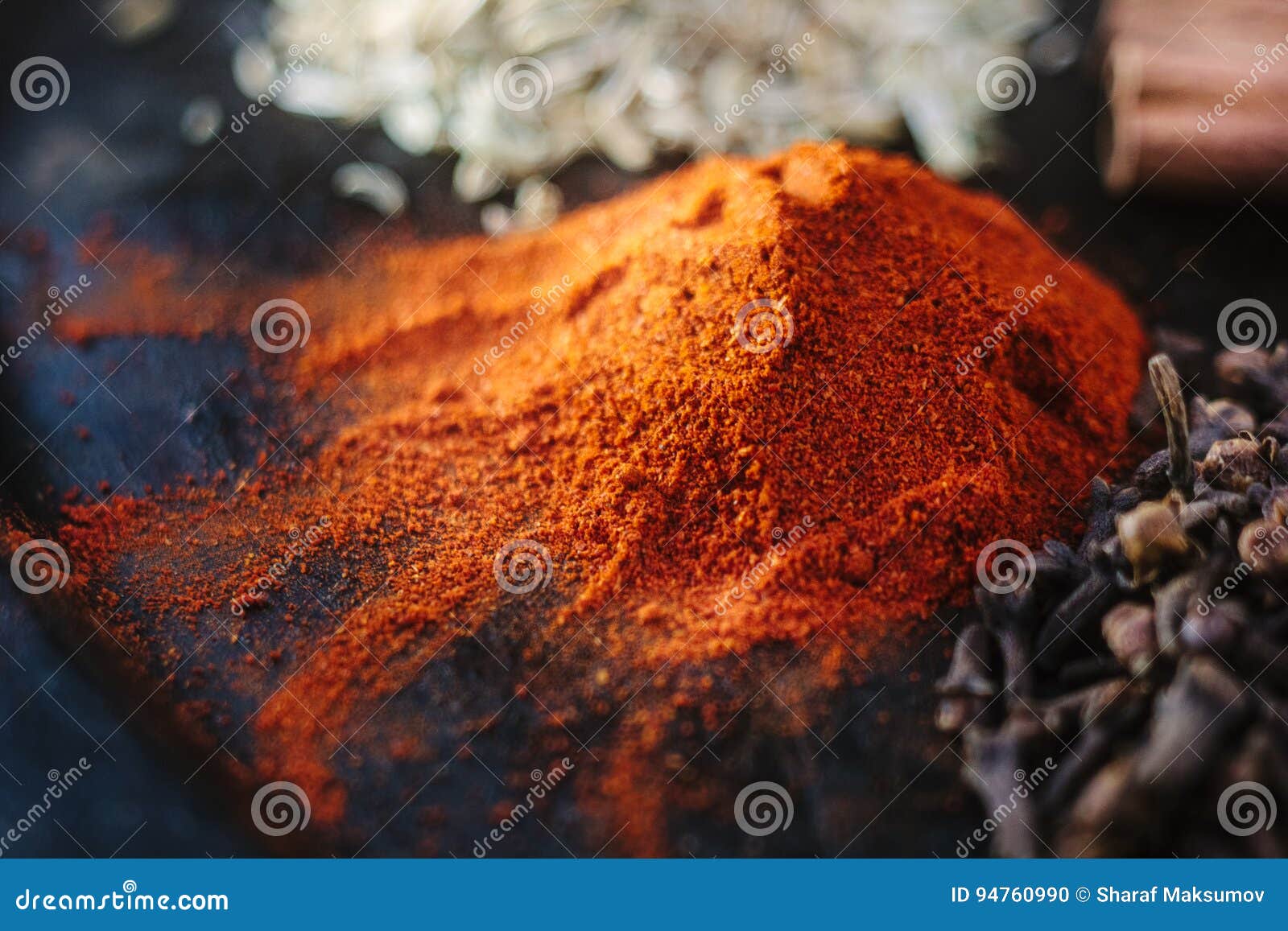 Grounded Chili Pepper on Black Rustic Surface, Surrounded by Spices
