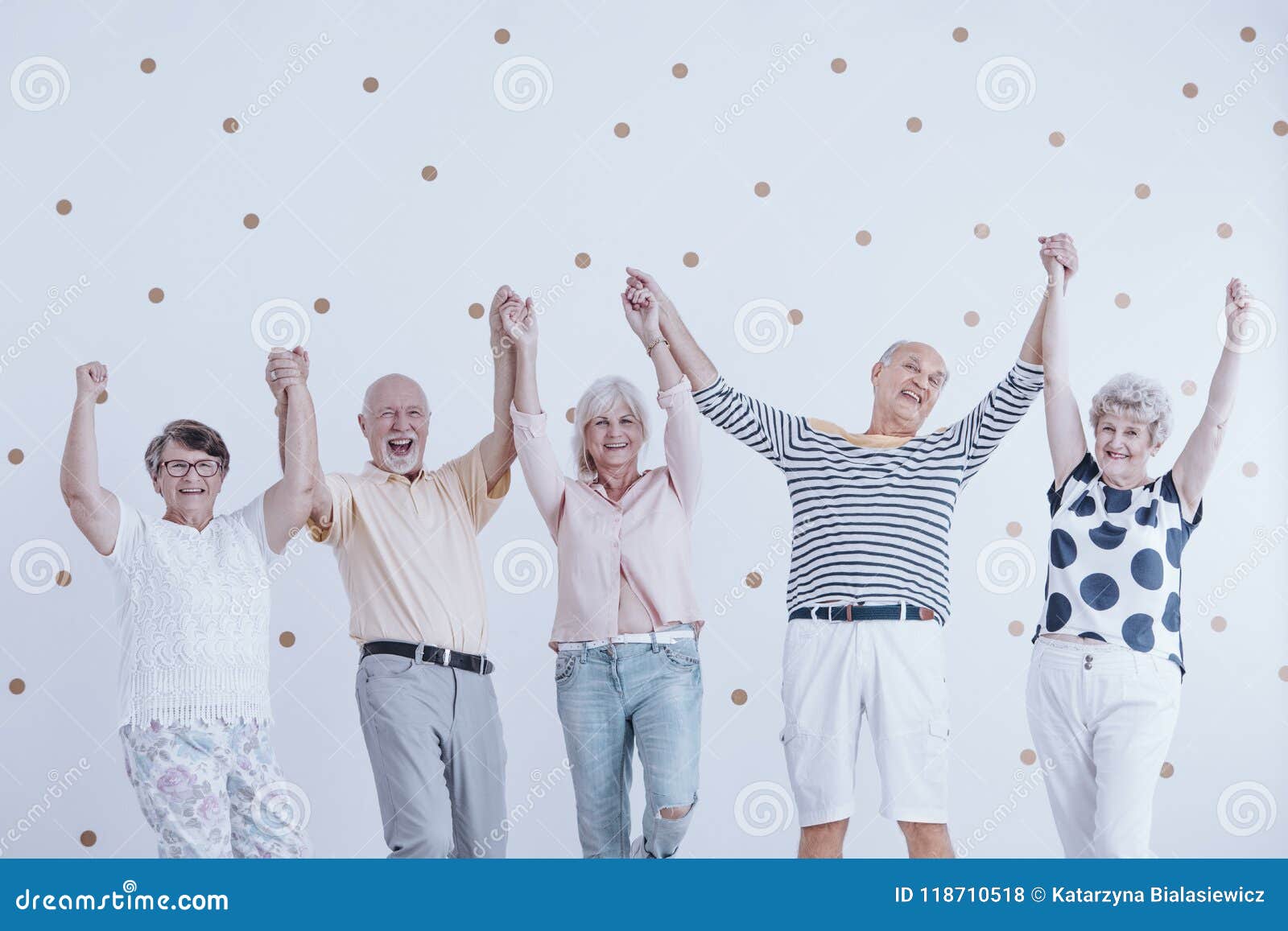 group of active elderly people holding hands up and enjoying meeting