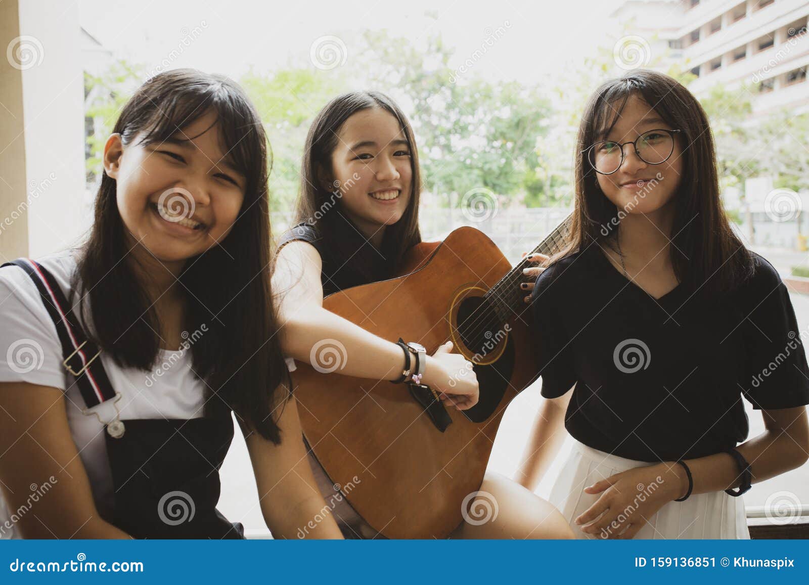 group of asian teenager standing outdoor plying spanish guitar