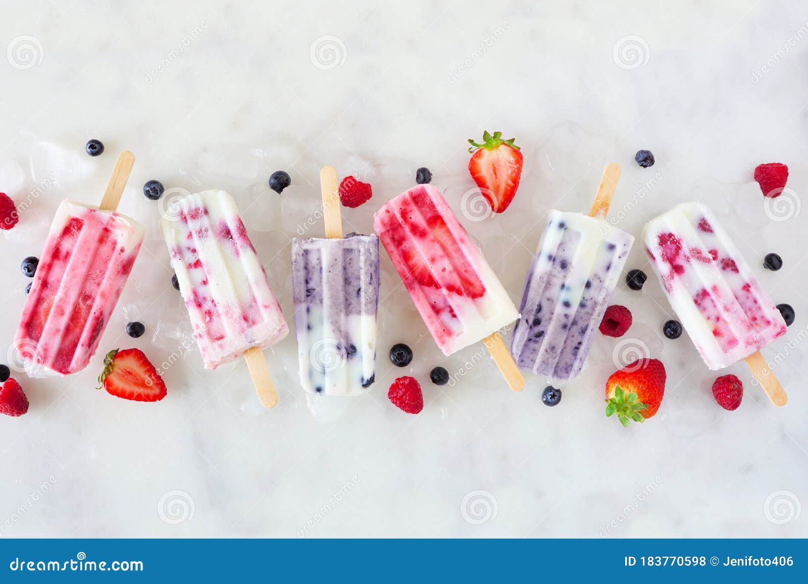 assorted berry fruit yogurt popsicles, top view in a row over marble