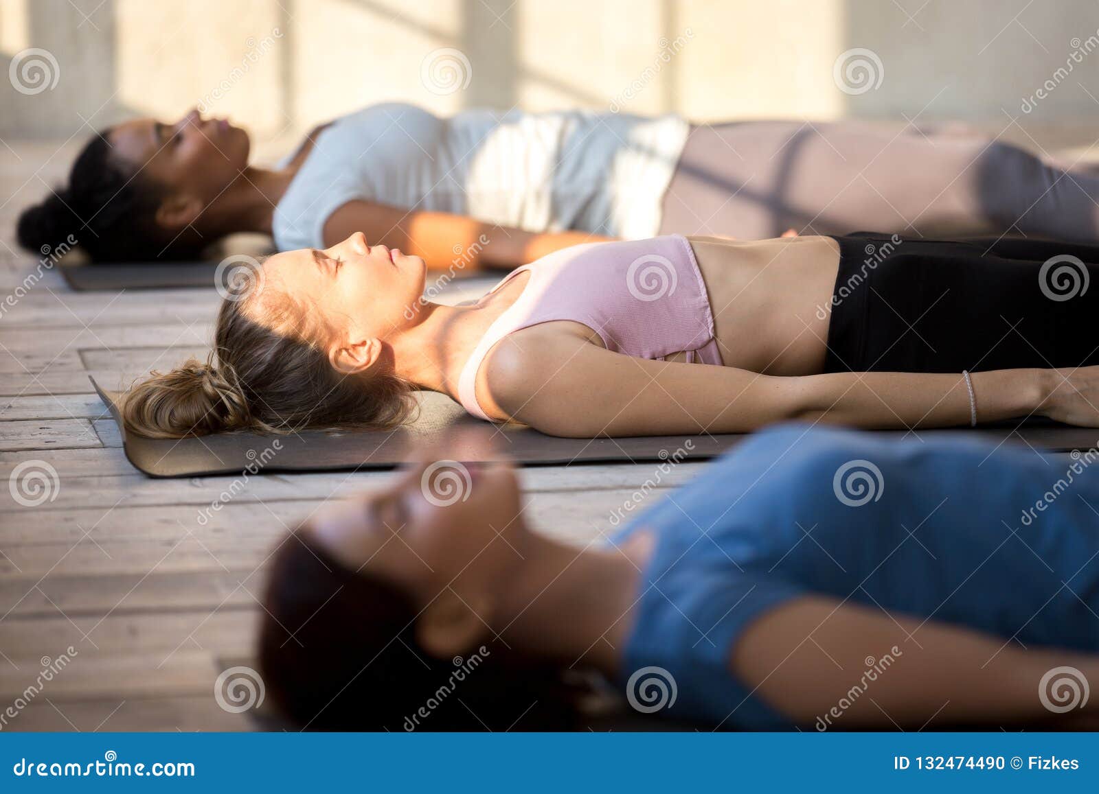 group of attractive women practicing yoga in dead body pose