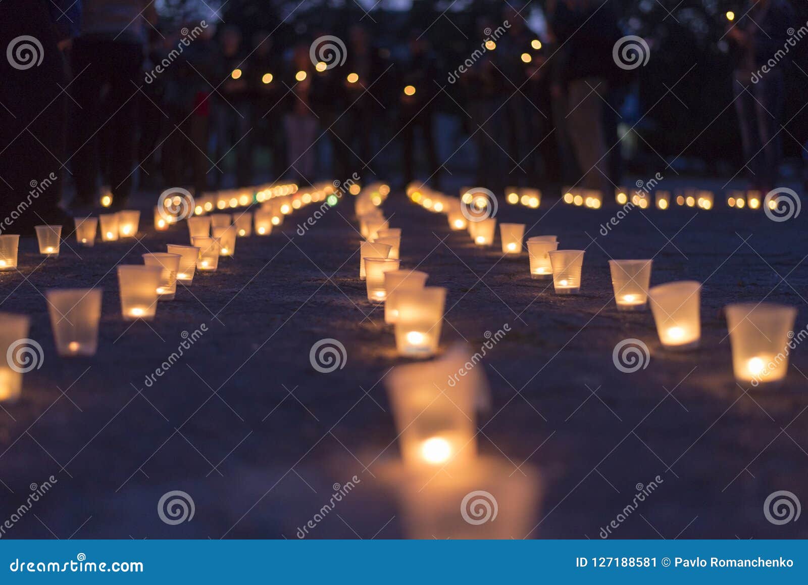 a group of candles burning in street and people holding candles in the background. day of memory of the bereaved