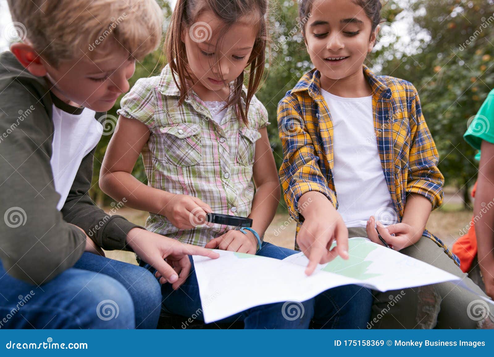group of children on outdoor activity camping trip looking at map together