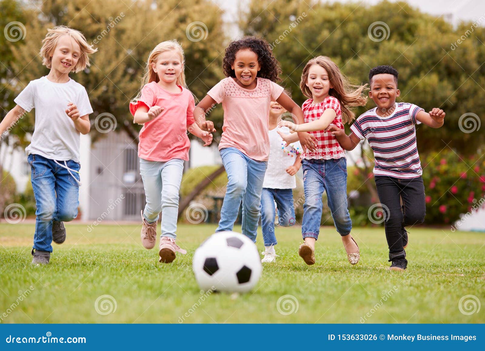 group of children playing football with friends in park