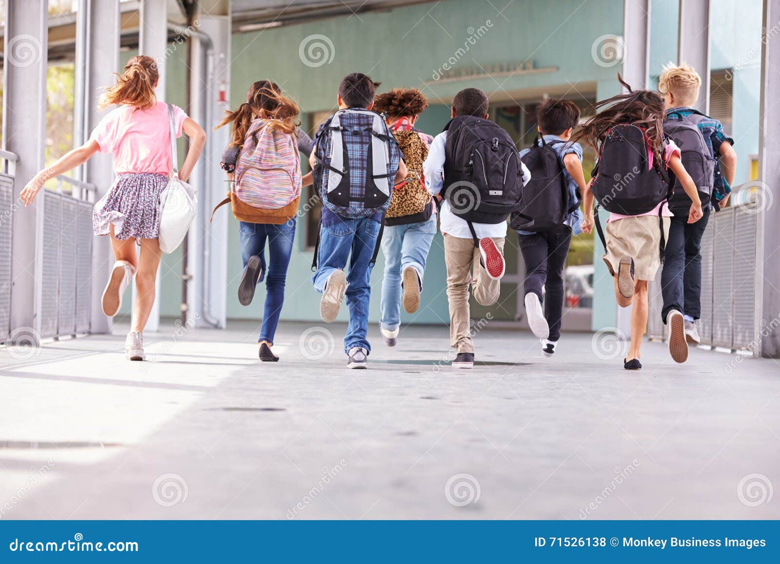 group of ary school kids running at school, back view