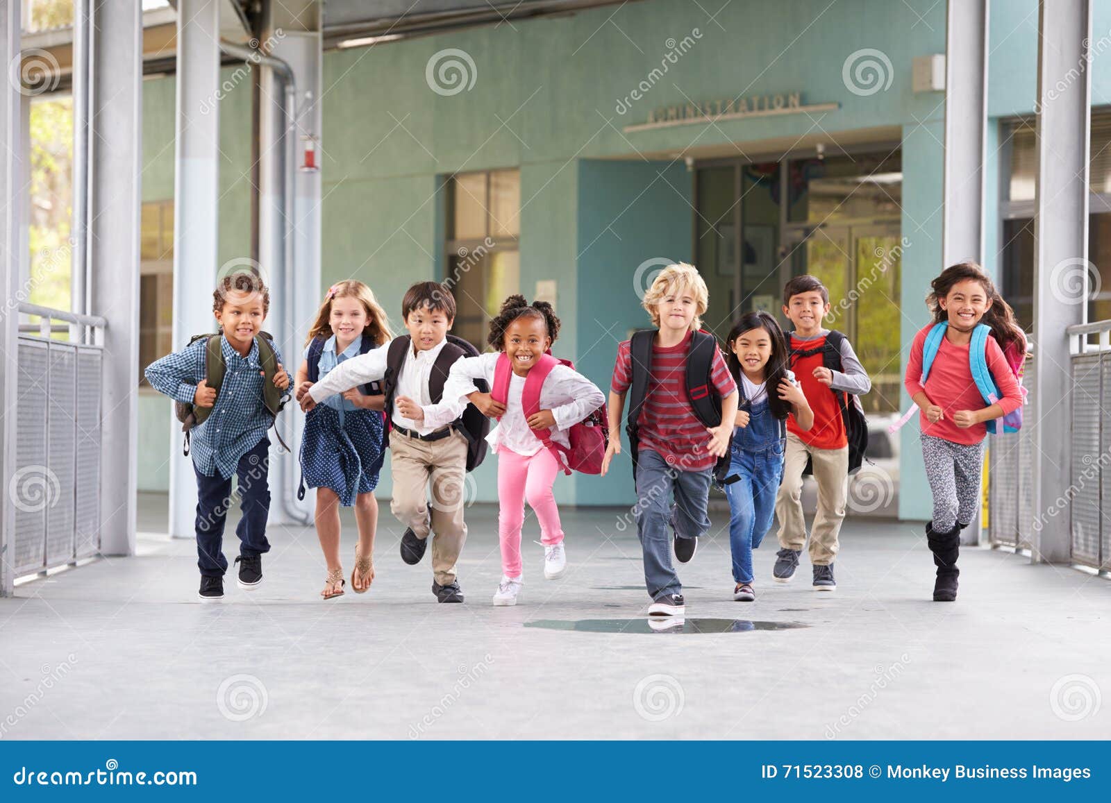 group of ary school kids running in a school corridor
