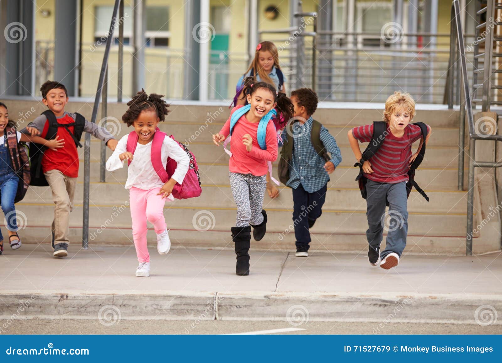 a group of ary school kids rushing out of school