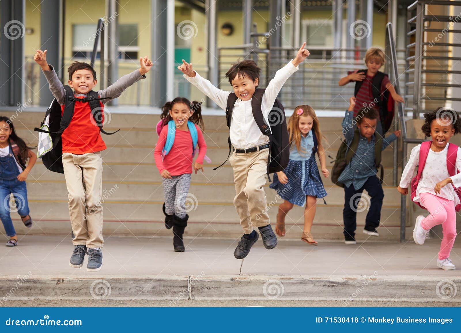 a group of energetic ary school kids leaving school