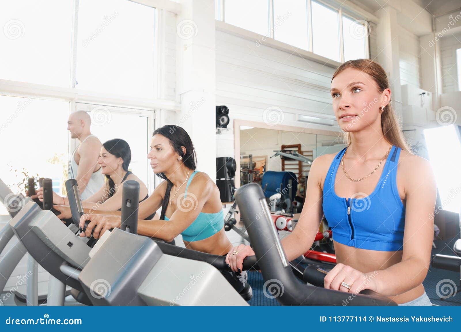 Group of Four People in the Gym, Exercising Their Legs Doing Cardio ...