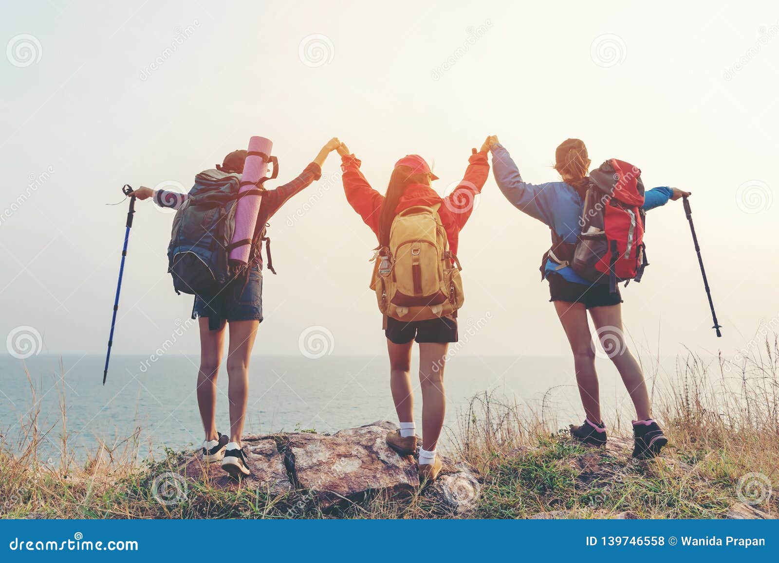 group friend team asian young women of hikers walking adventure with backpack on a mountain at sunset. traveler life going trip ca