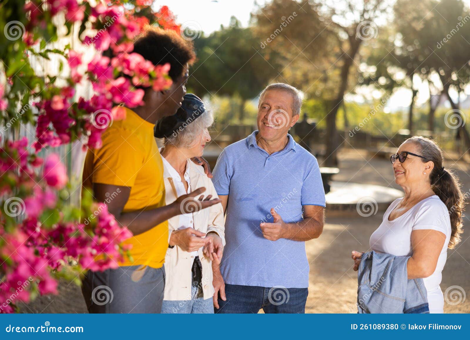 A Group of Friendly Multiracial Mixed-sex Mature Adult People Standing Outside Talking To Each Other Stock Photo picture
