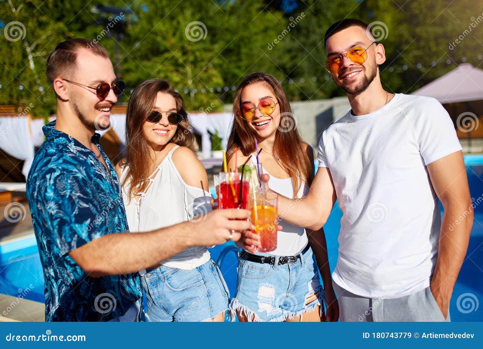 Group Of Friends Having Fun At Poolside Summer Party Clinking Glasses