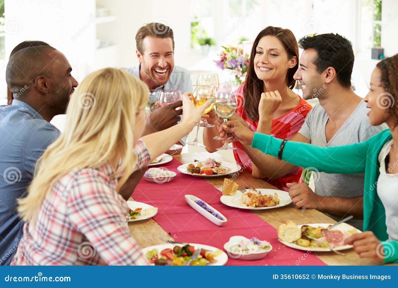 Group Of Friends Making Toast Around Table At Dinner Party Stock Photo