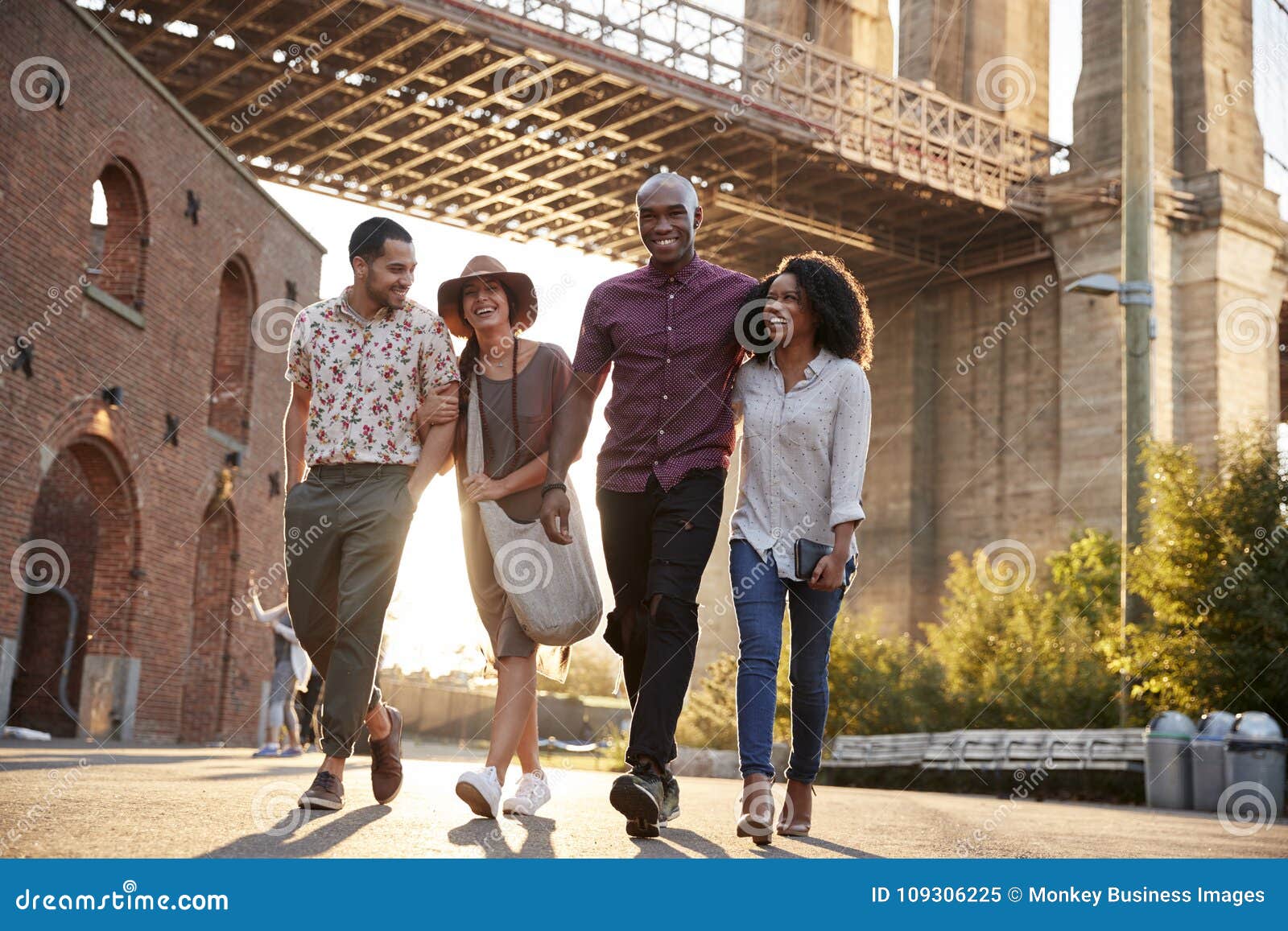 Group of Friends Walking by Brooklyn Bridge in New York City Stock