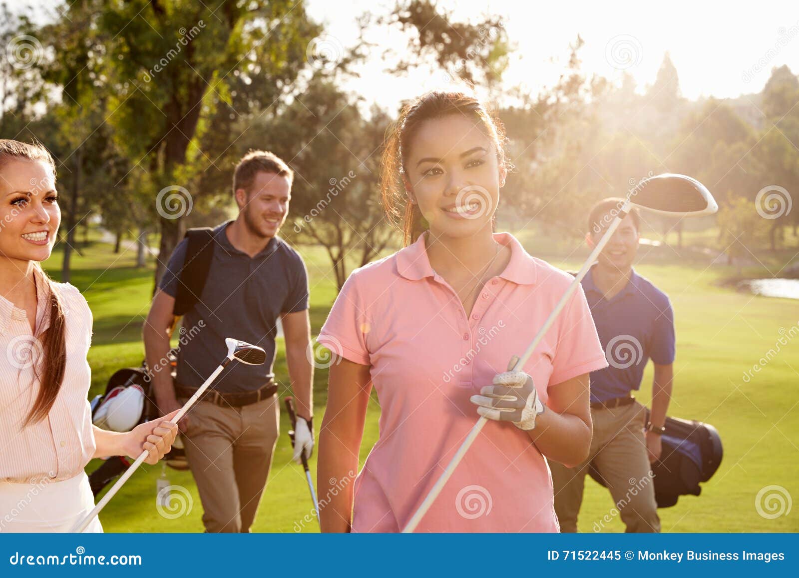 Group of Golfers Walking Along Fairway Carrying Golf Bags Stock Image