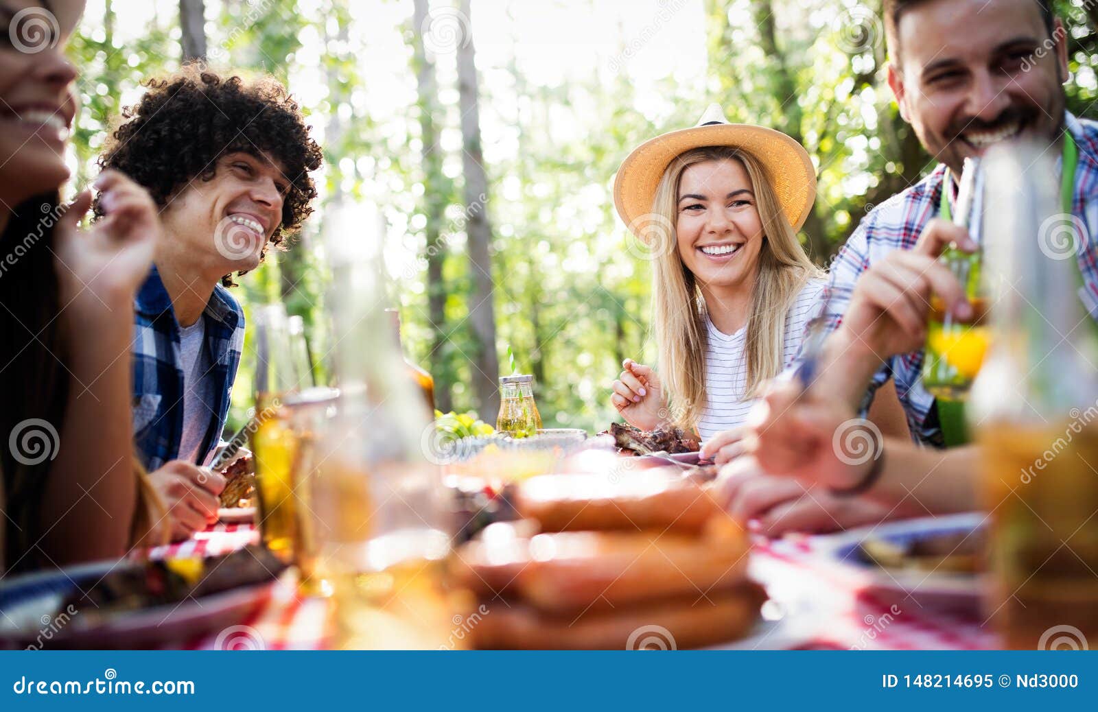 Group of Happy Friends Eating and Drinking Beers at Barbecue Dinner