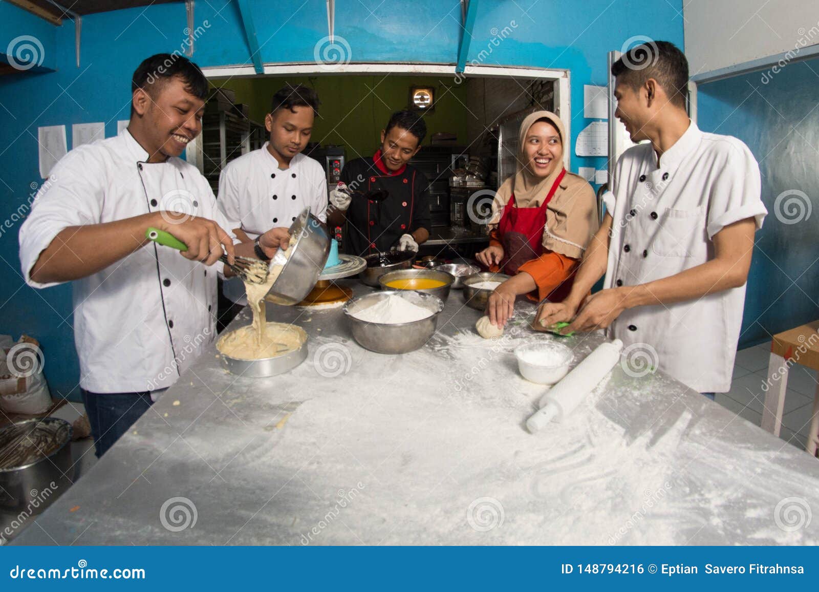 group of happy young asian pastry chef preparing dough with flour, profesional chef working at kitchen