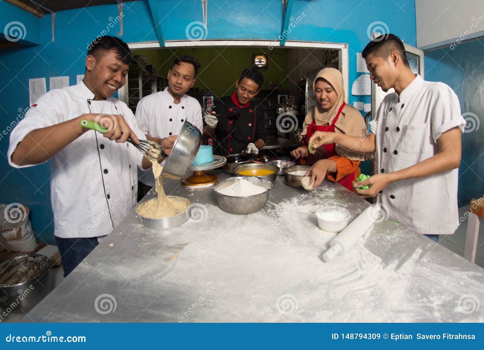group of happy young asian pastry chef preparing dough with flour, profesional chef working at kitchen